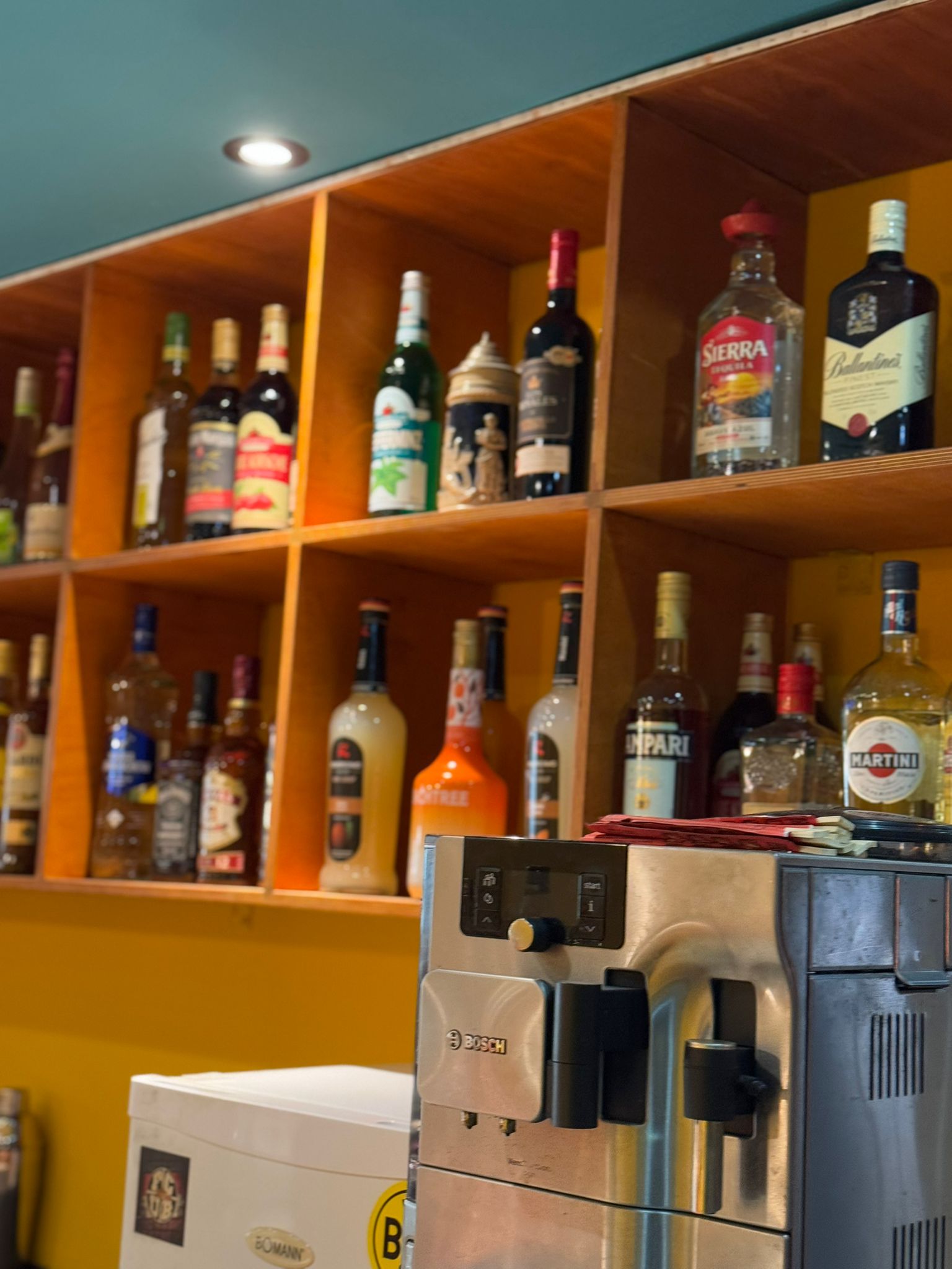 Nahaufnahme der Spirituosen-Sammlung mit Premium-Marken und Kaffeemaschine