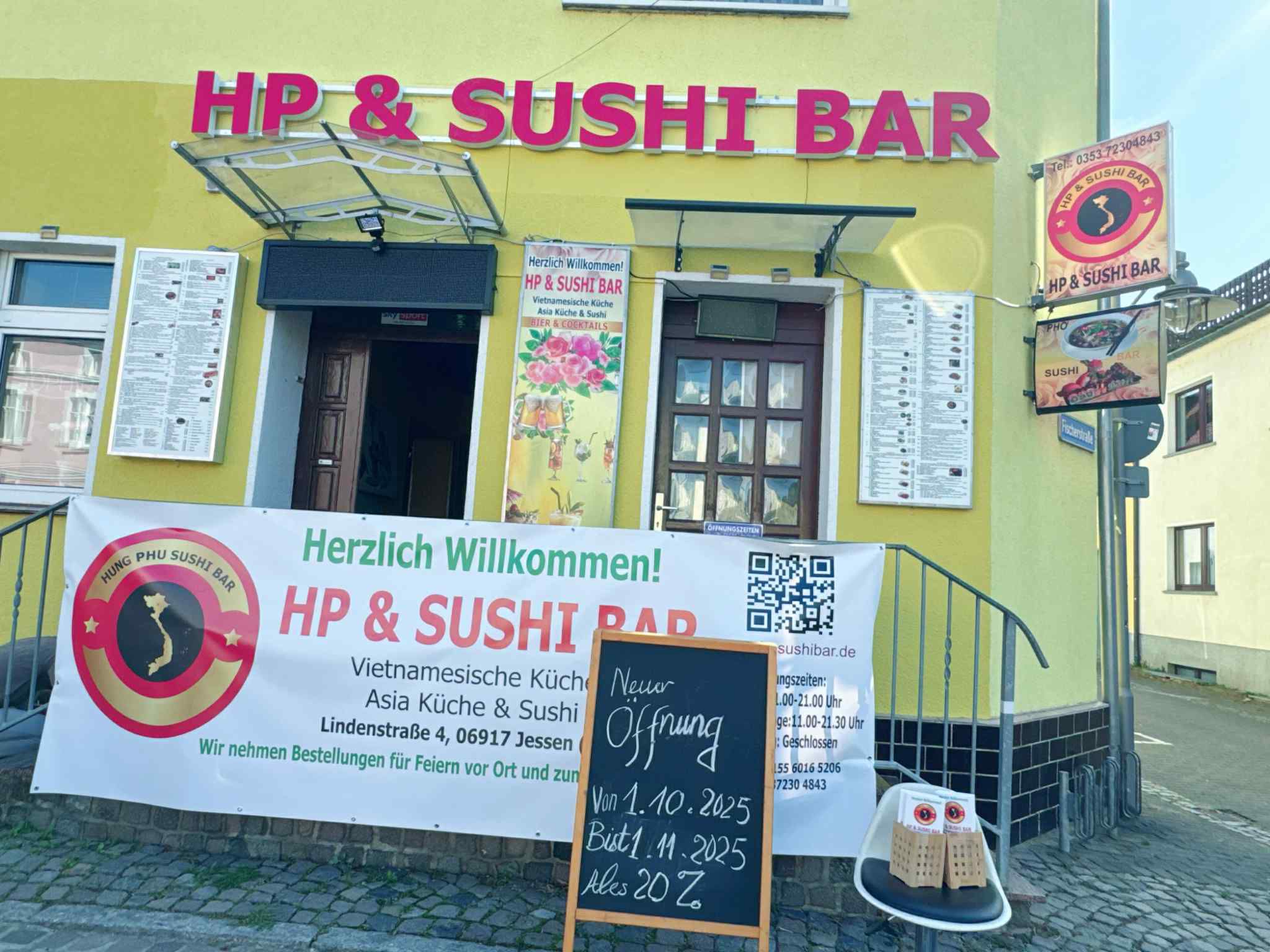 Eingang des HP & Sushi Bar mit Speisekarten und Willkommensbanner